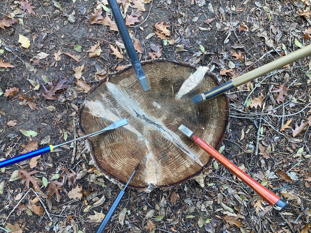 Camping axes lodged in top of log splitting wood at campsite