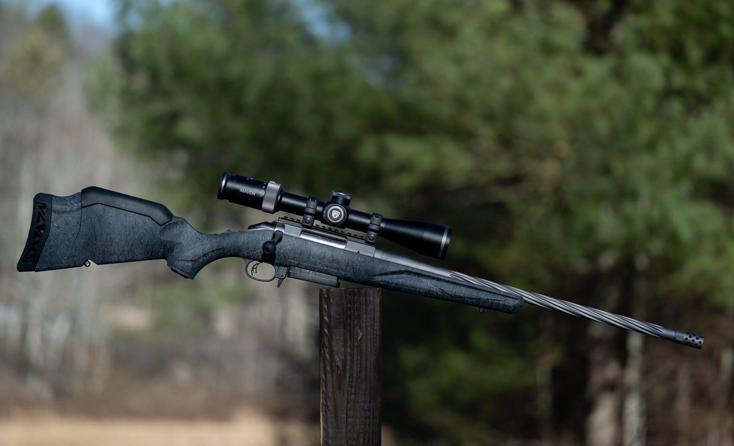 The new Ruger American Gen II rifle resting on a post with woods in background