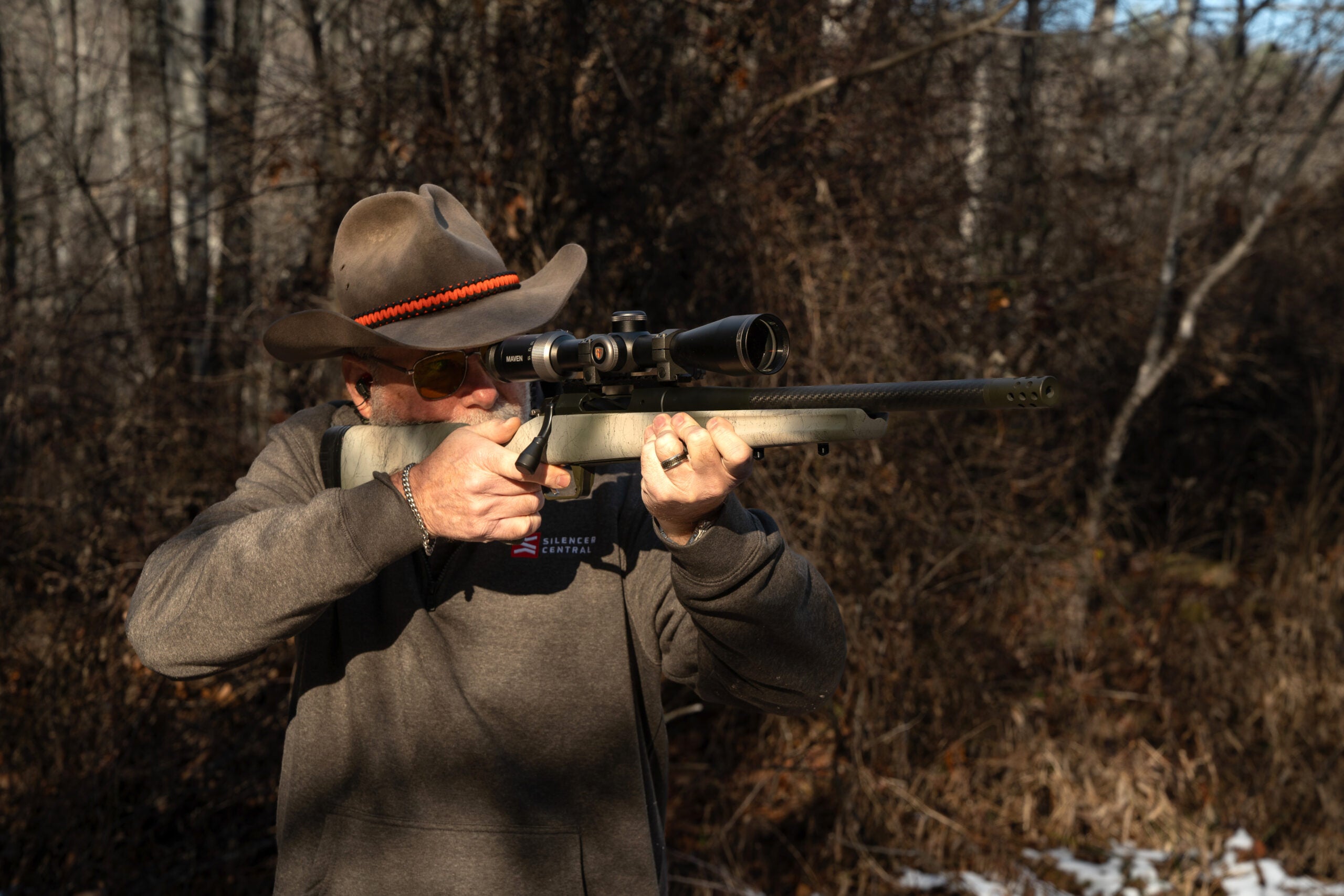 Shooter firing the Springfield Armory Model 2020 Redline rifle offhand with woods in background
