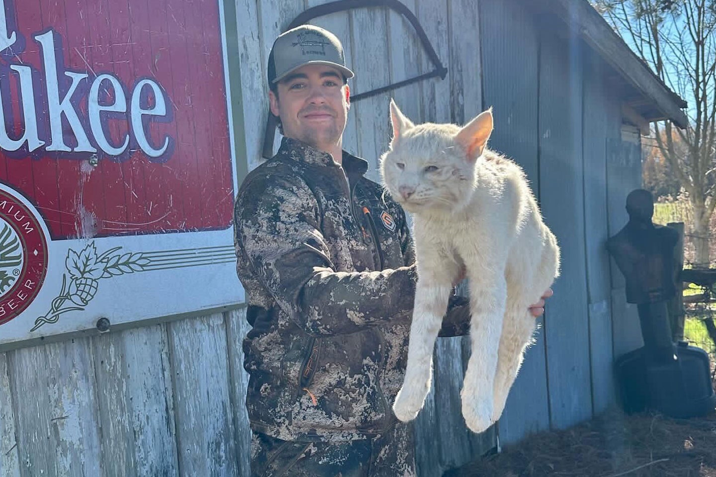 A hunter poses with an albino bobcat.