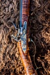 An ornately decorated flintlock rifle lying on a buffalo hide