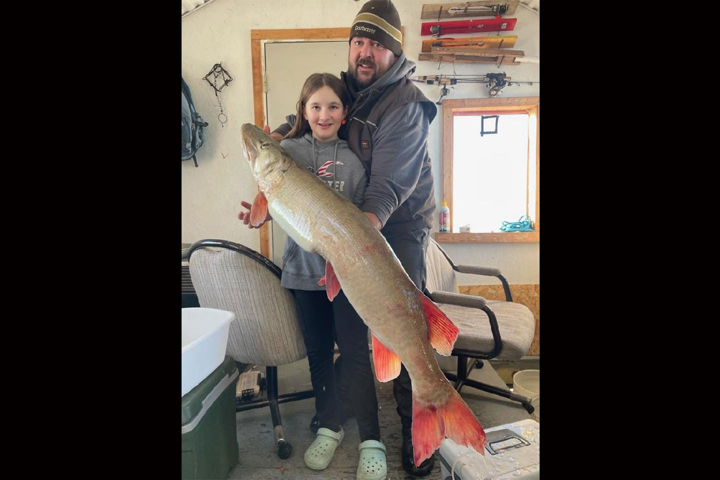 A young angler poses with a 34 pound muskie caught while ice fishing.