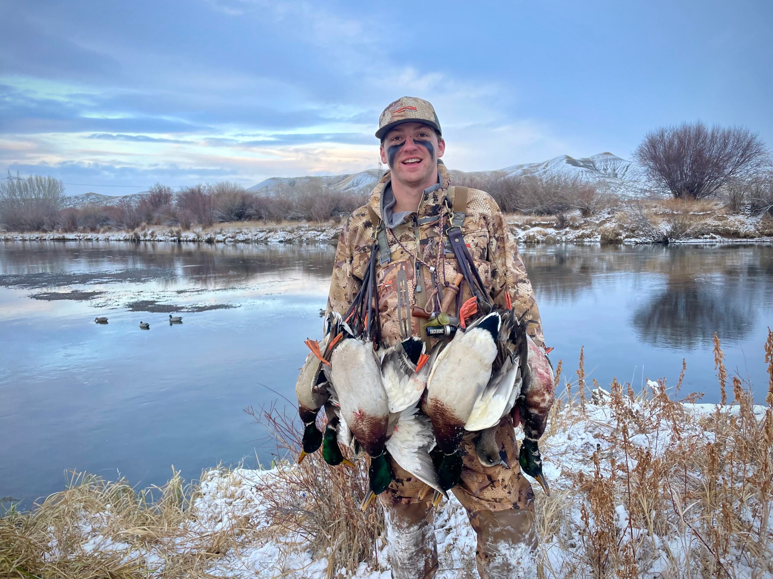 Hunter standing with a full strap of ducks