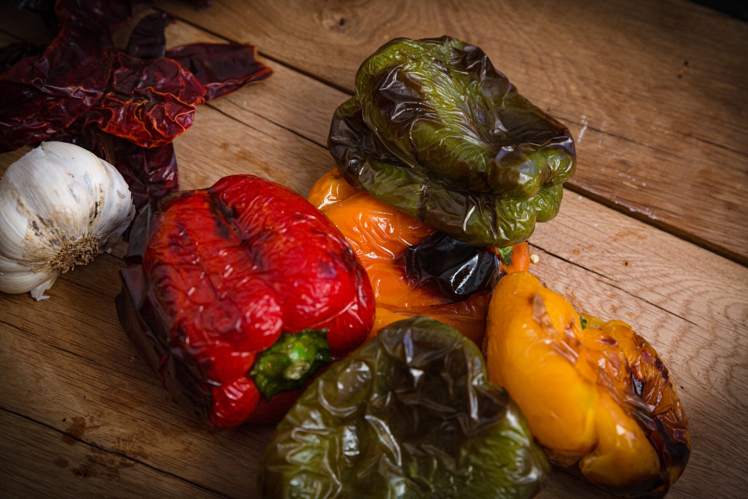 An assortment of roasted bell peppers resting on a wooden cutting board.