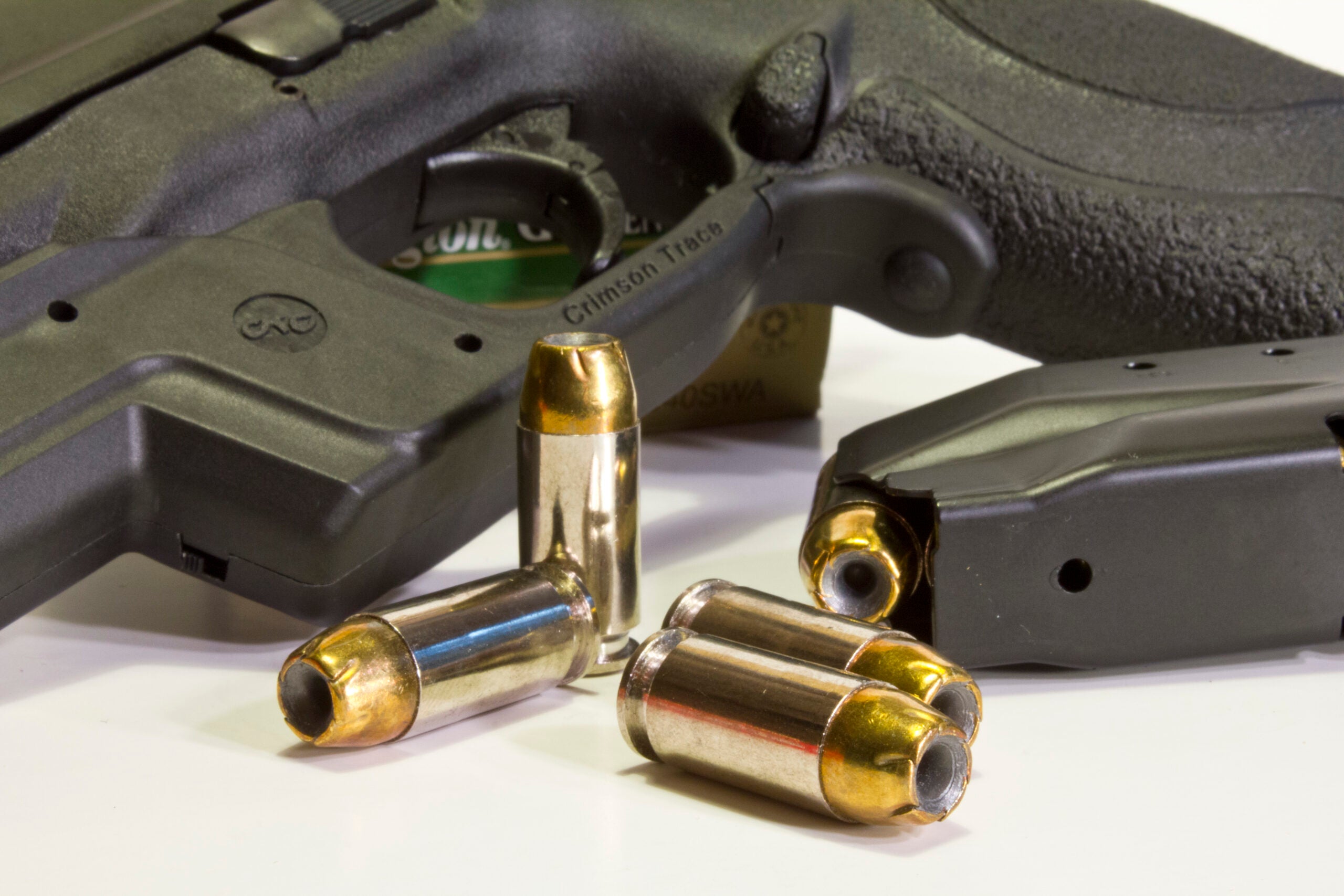 40 S&W cartridge lying near a pistol and magazine on white background