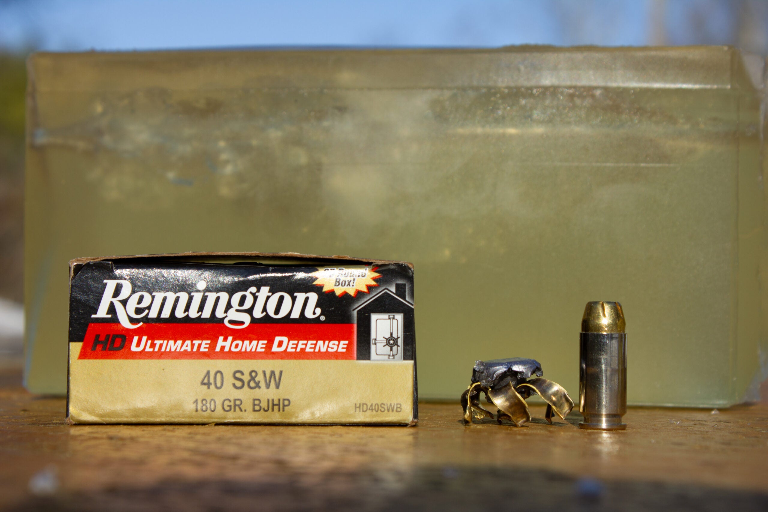 Box of 40 S&W ammo, a fired bullet, and unfired cartridge sit in front of a block of ballistics gel
