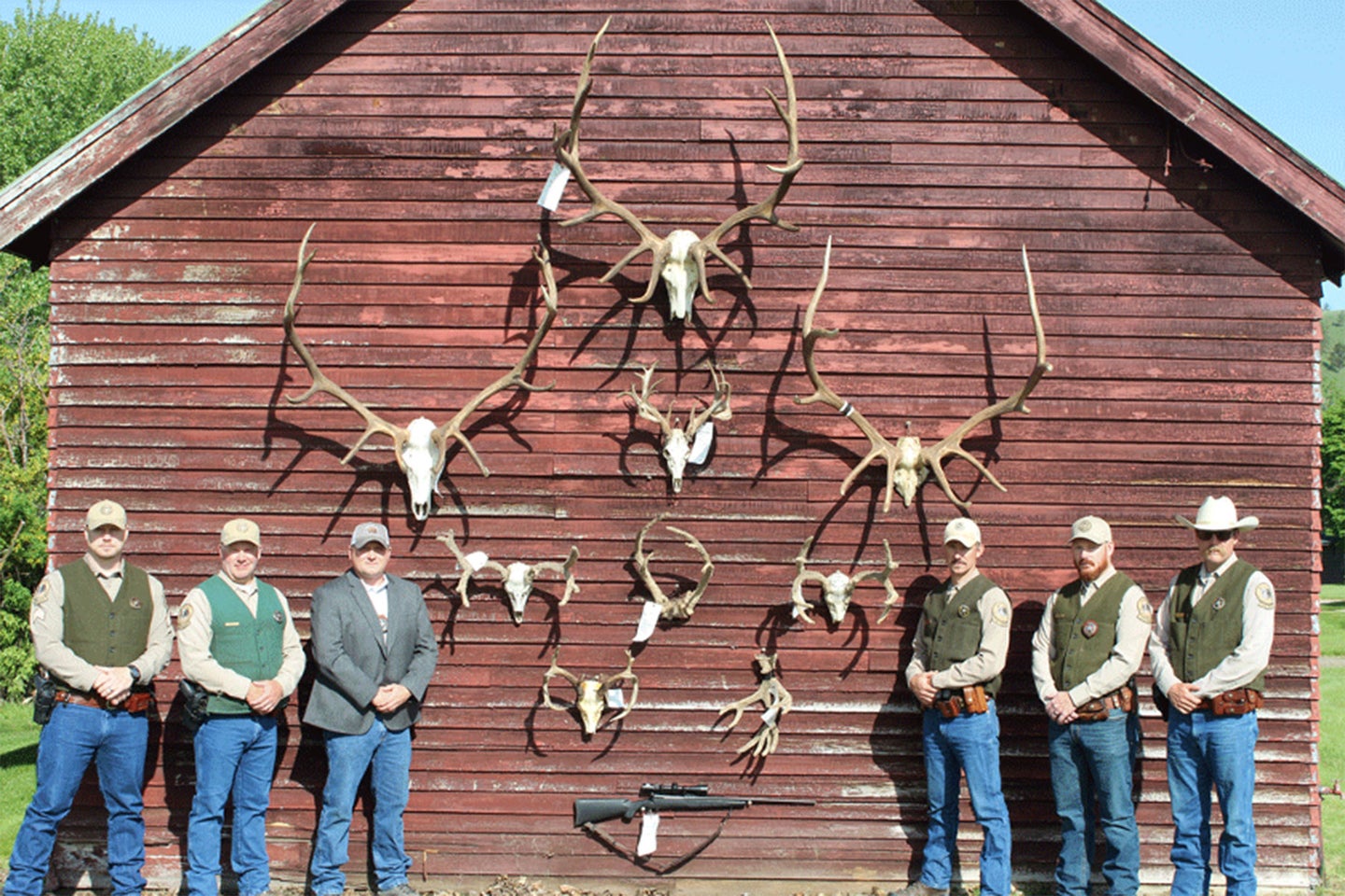 Wardens pose with poached elk and deer.