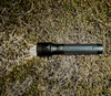 Ledlenser P7R Flashlight turned on laying on grass