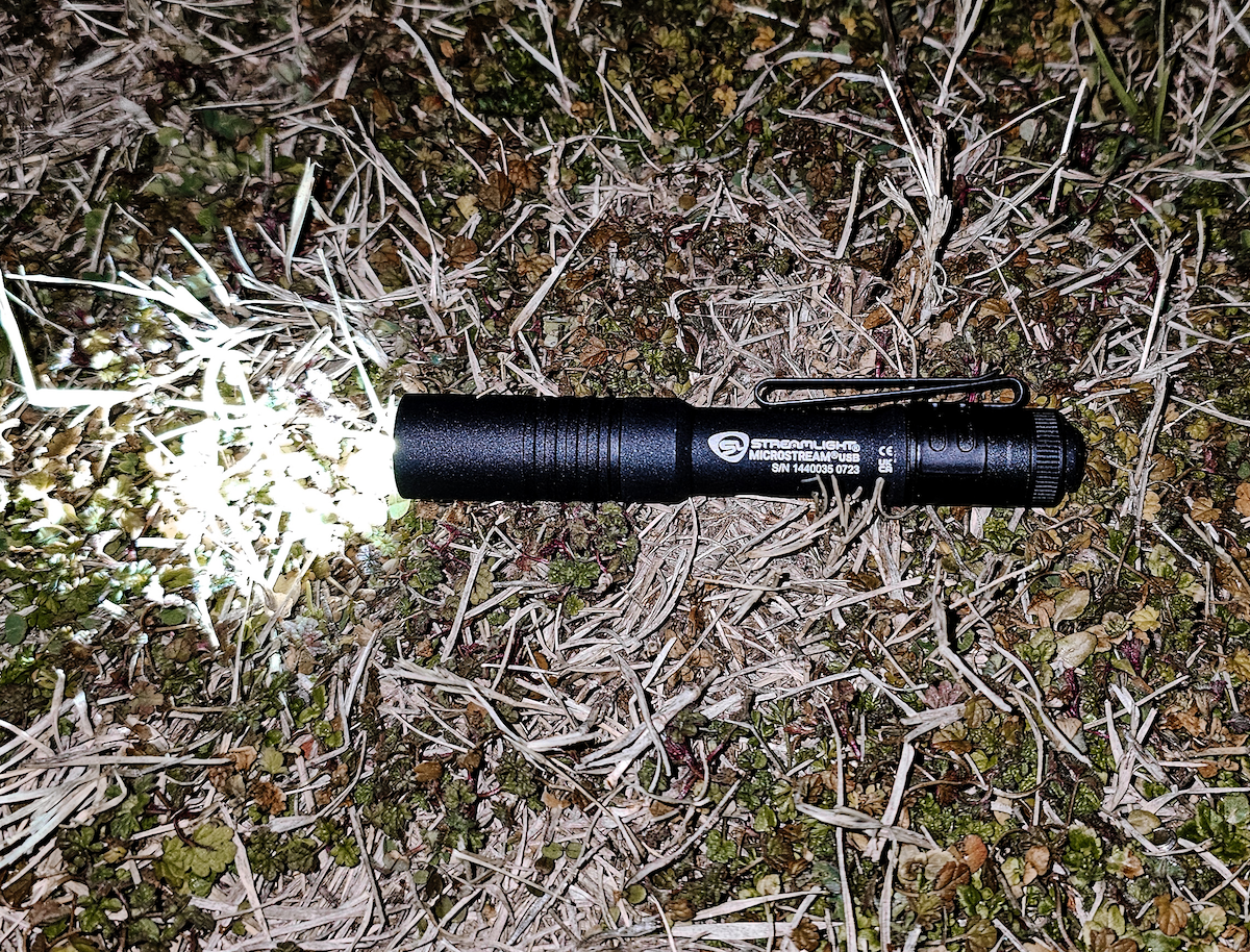 Streamlight Microstream Flashlight turned on laying on grass