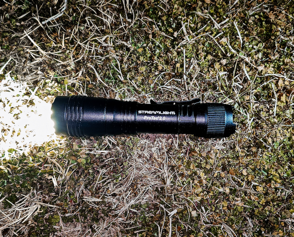 Streamlight ProTac 2.0 Flashlight turned on laying on grass