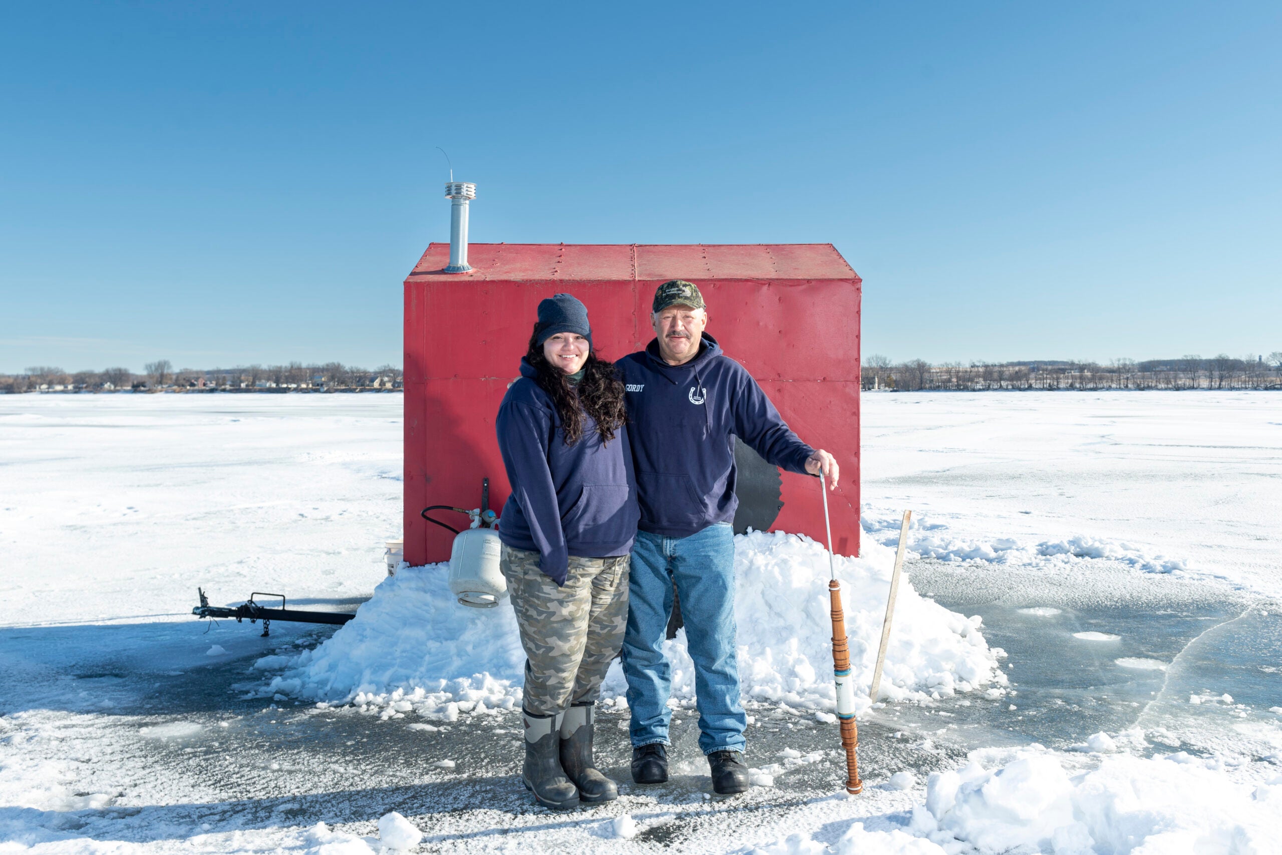 Wisconsin spearfishers pose on the ice in front of a portable shanty. 