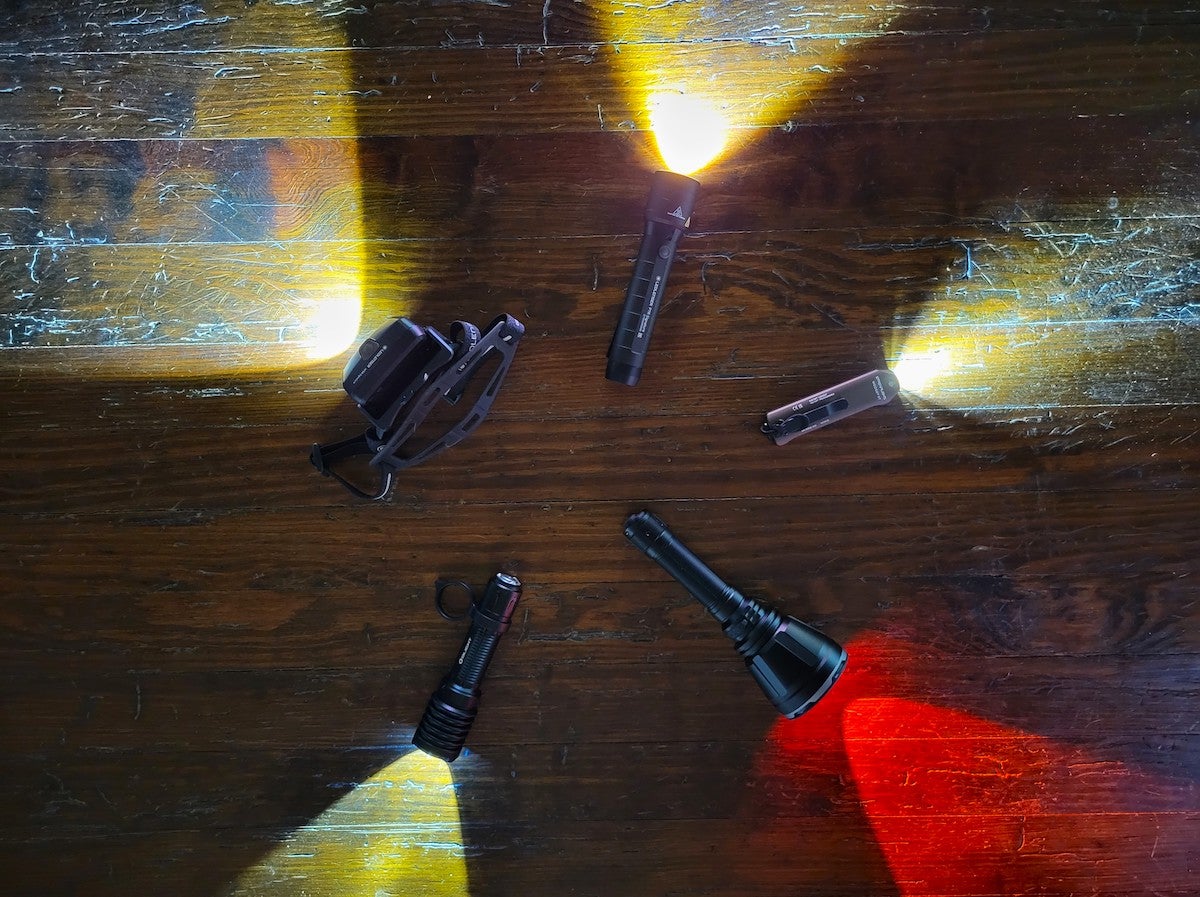 Hunting flashlights arranged on wood floor with light beams