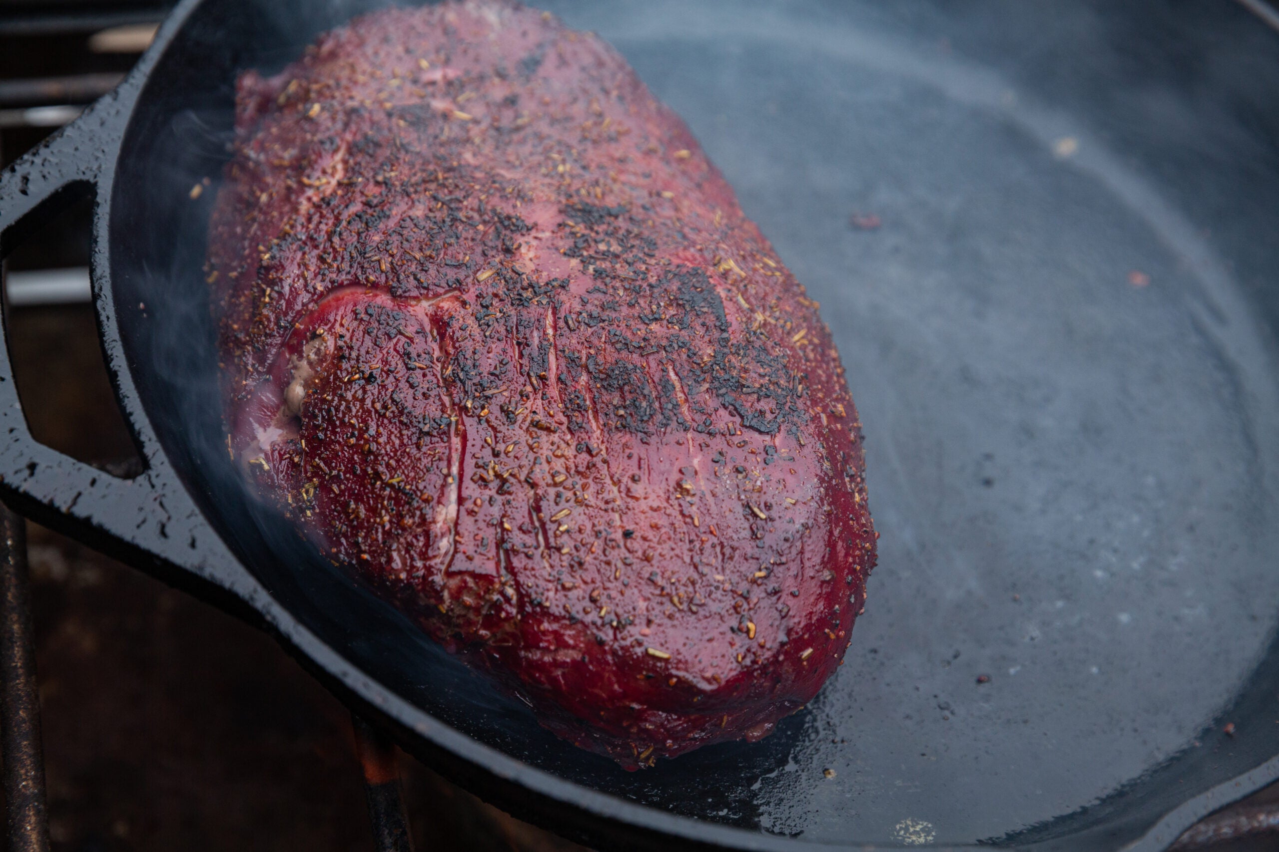 A venison top round cooks in a cast-iron skillet