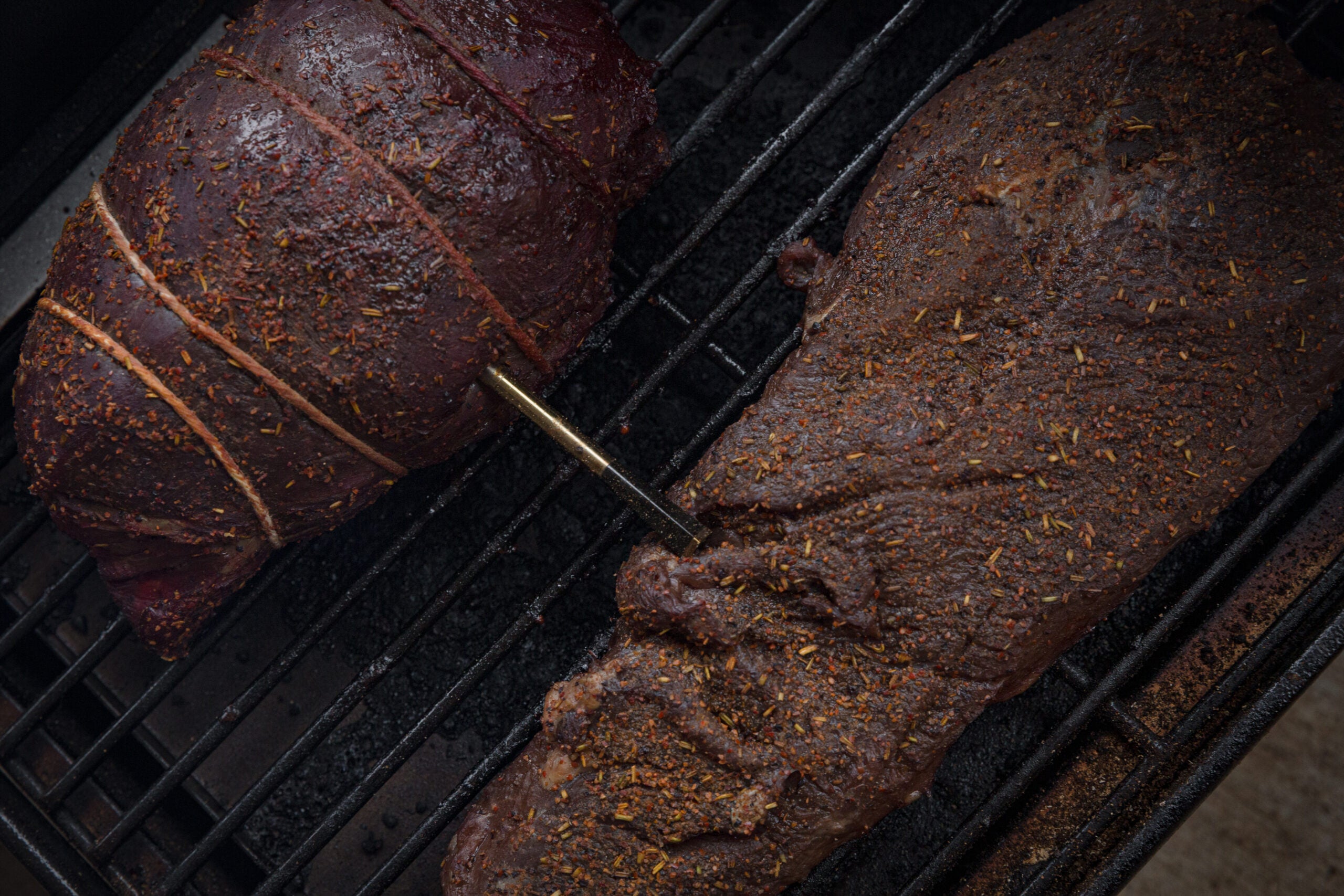 Two whitetail deer venison roasts cooking on a grill.