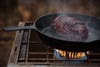 A venison serloin from a whitetail deer cooks in a cast iron pan.