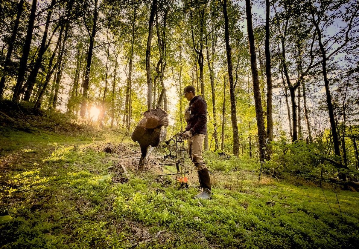 Turkey hunter in the woods holding dead turkey