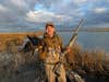 hunter holding black duck and shotgun