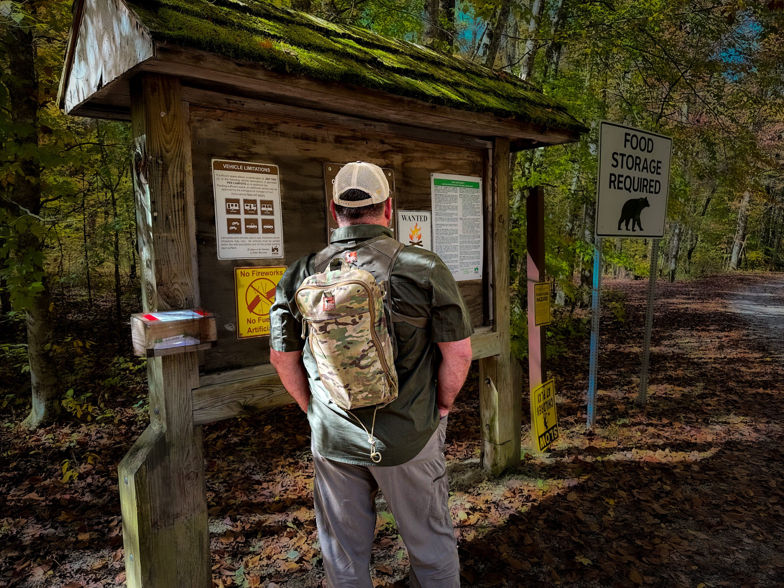 A hiker reads trail information on a bulletin board at a trailhead.