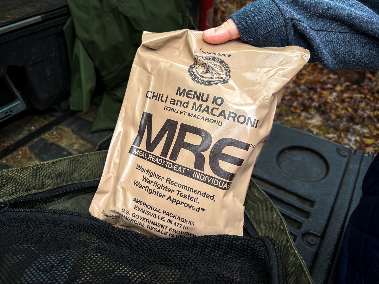 A hiker reaches for an MRE bag on a outdoor trip