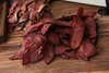 A pile of thin slices of pastrami goose meat on a cutting board