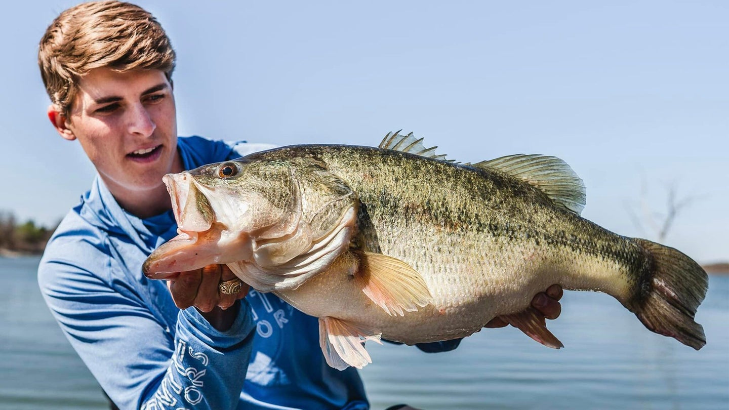 Texas angler Tyler Anderson hefts a giant largemouth bass with lake in background
