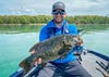 Lake Michigan angler Ben Nowak hefts a big smallmouth bass while sitting in a boat