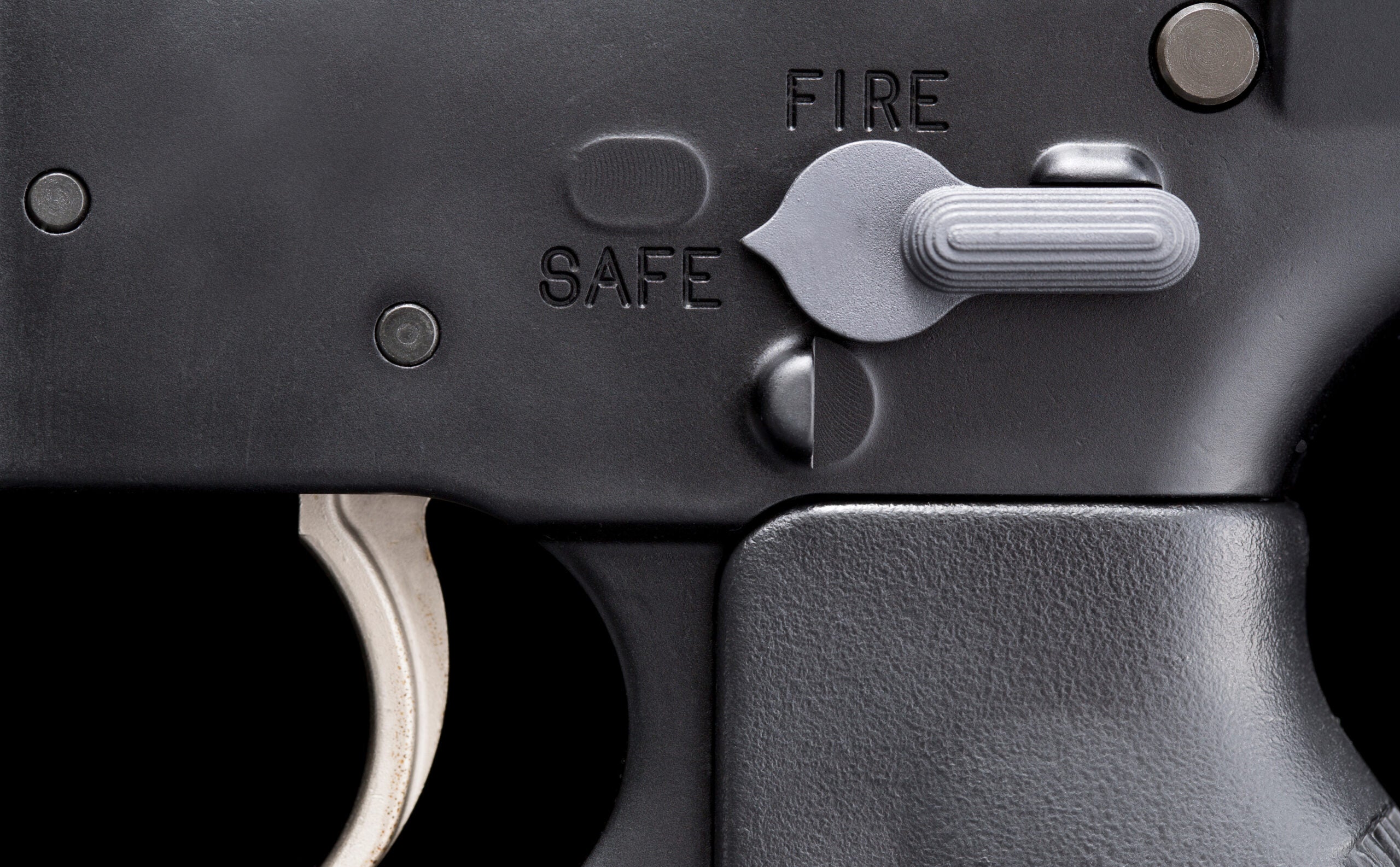 Closeup of a firearm safety, showing the both the safe and fire positions