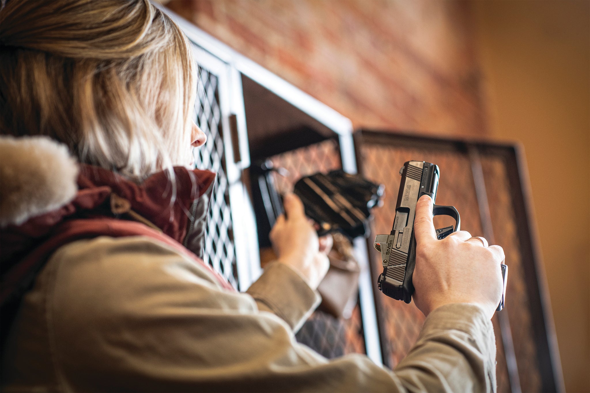 A woman removes a handgun from a gun locker