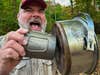 A man bangs two metal cups together to demonstrate how to avoid a bear attack