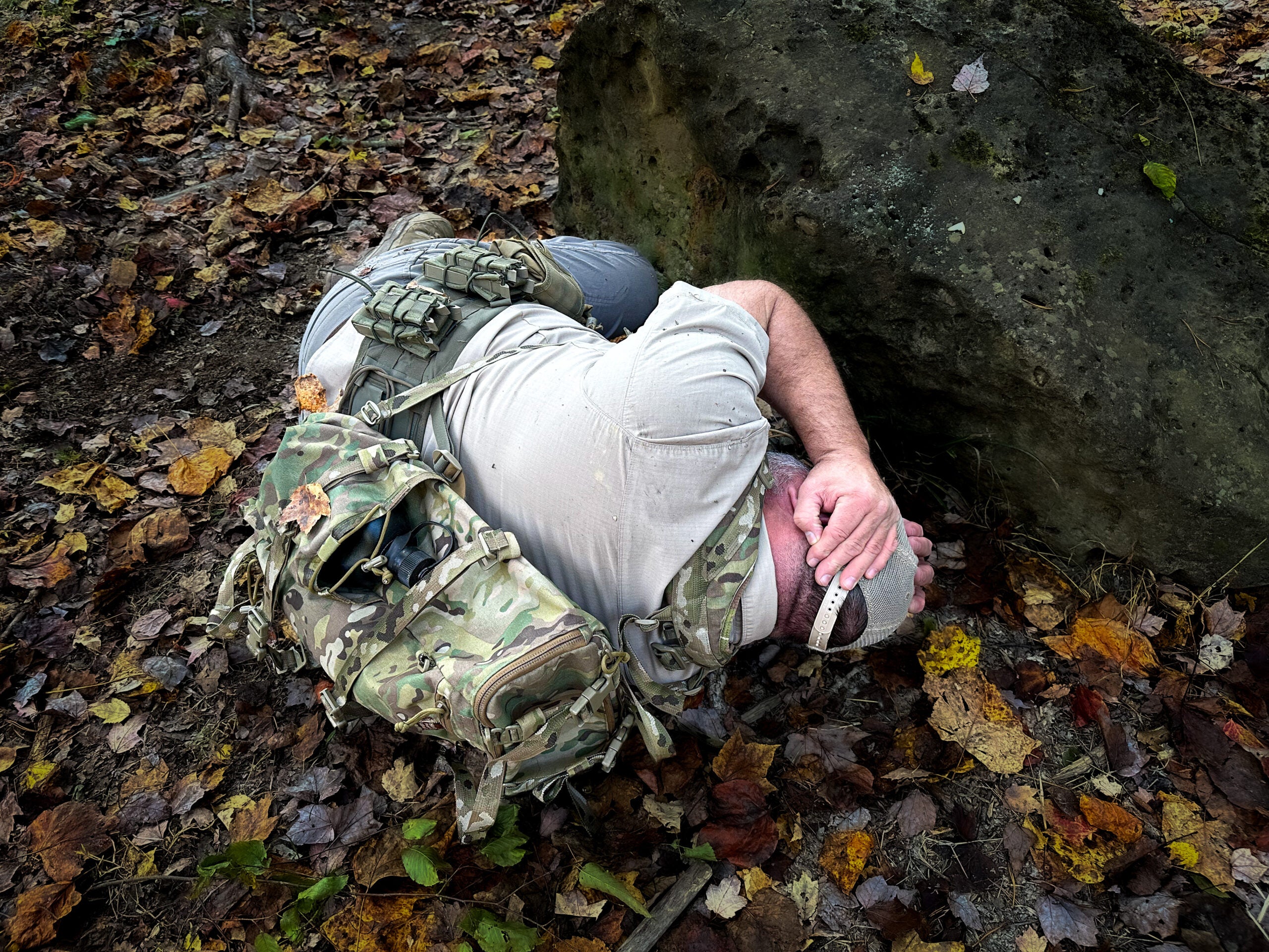 A man pretends to play dead by lying on the ground and covering his head.