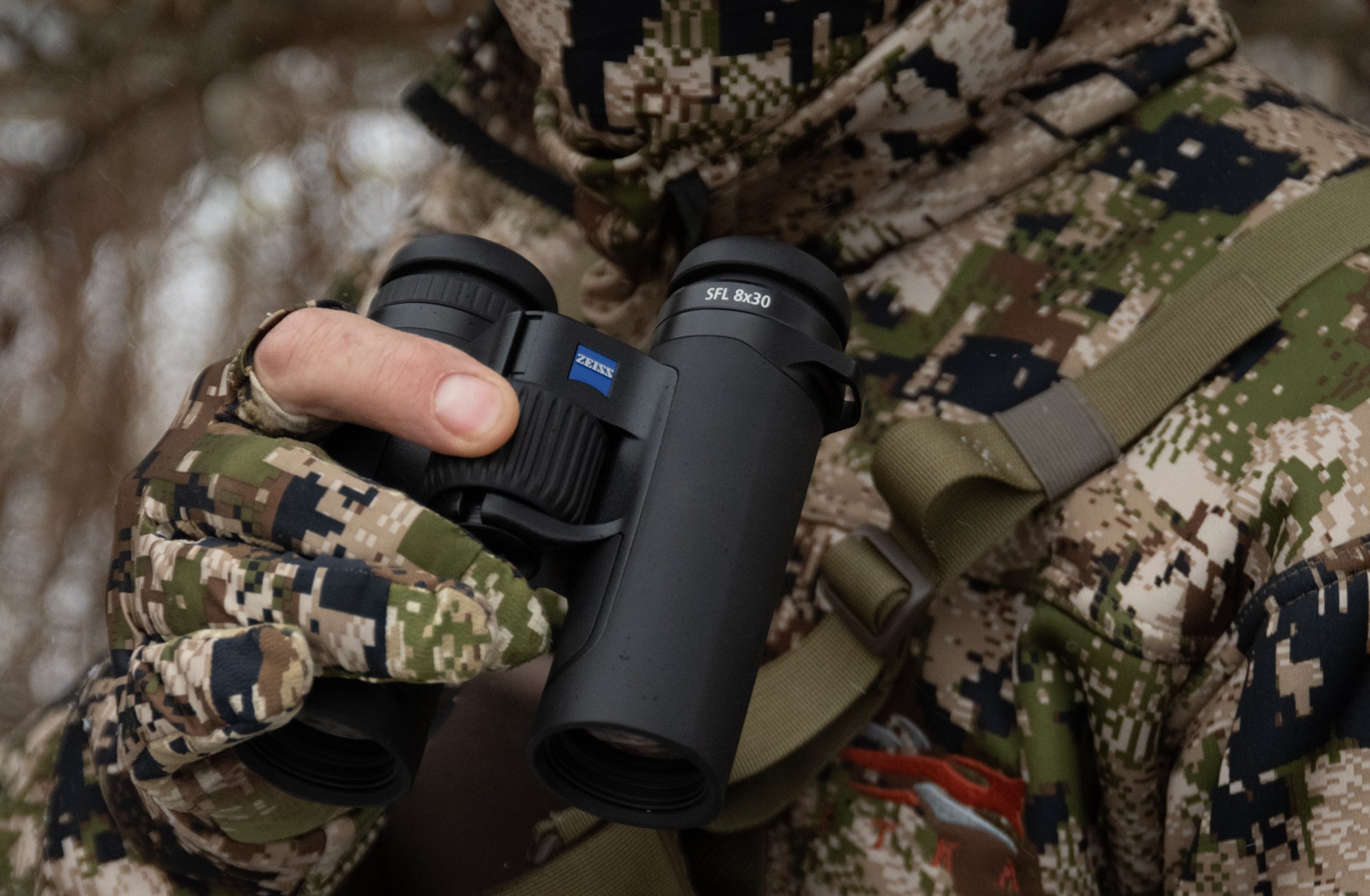 A hunter holding a pair of Zeiss 10x30 binoculars.