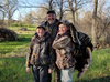 An adult hunter with two young boys, one of them with a tom turkey slung over his shoulder