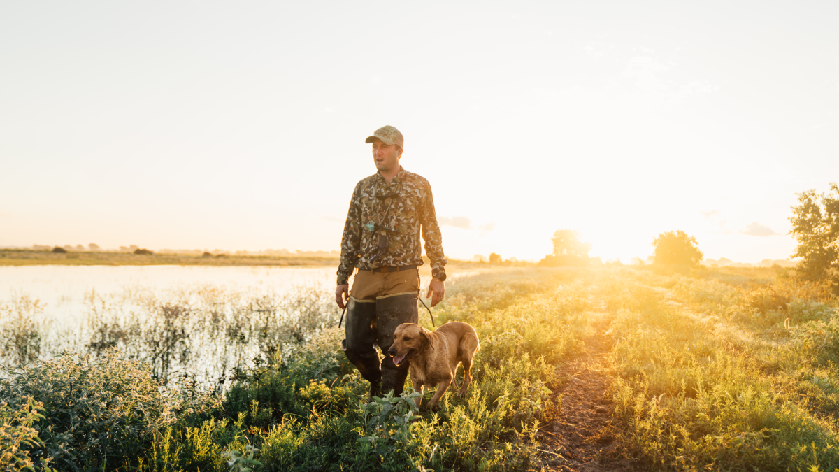 Sim Whatley, founder of Duck Camp, walking through field with dog