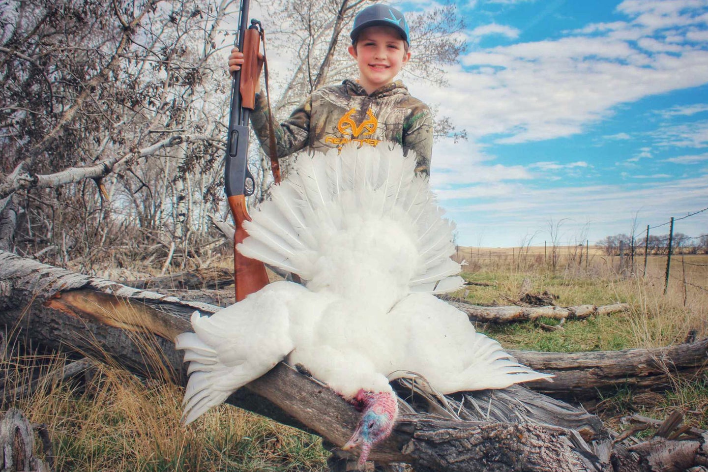 A young hunter poses with an all-white turkey after a successful hunting with his father.
