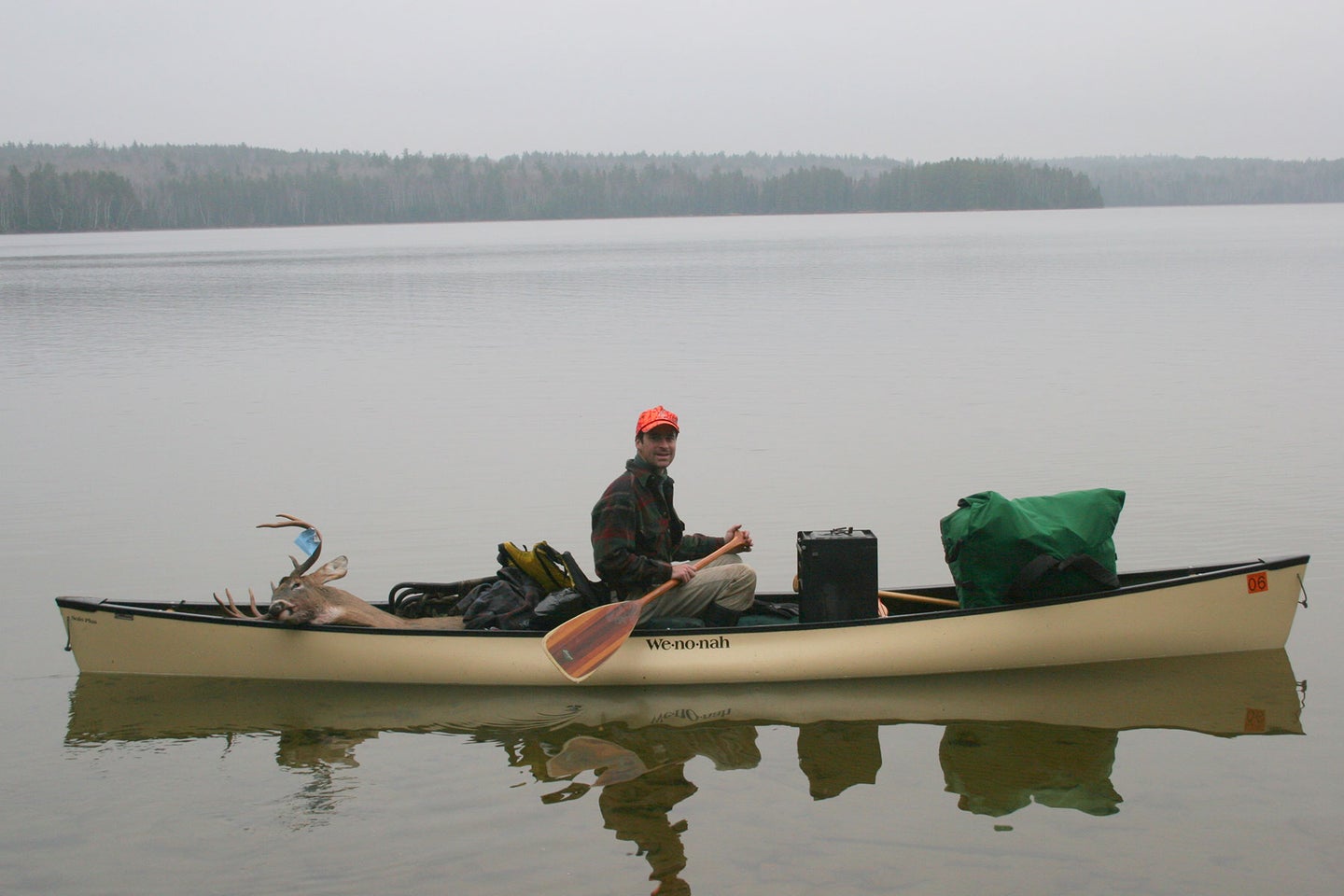 A hunter paddles a canoe with a whitetail deer tagged in the Boundary Waters Canoe Area Wilderness.