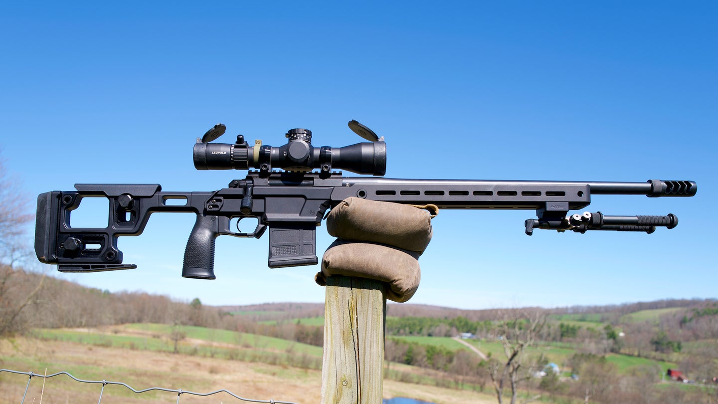 Aero Precision Solus Competition rifle balanced on a post with hills and sky in background.
