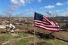 An American flag stands in from of the aftermath of a tornado in Dawson Springs, KY.