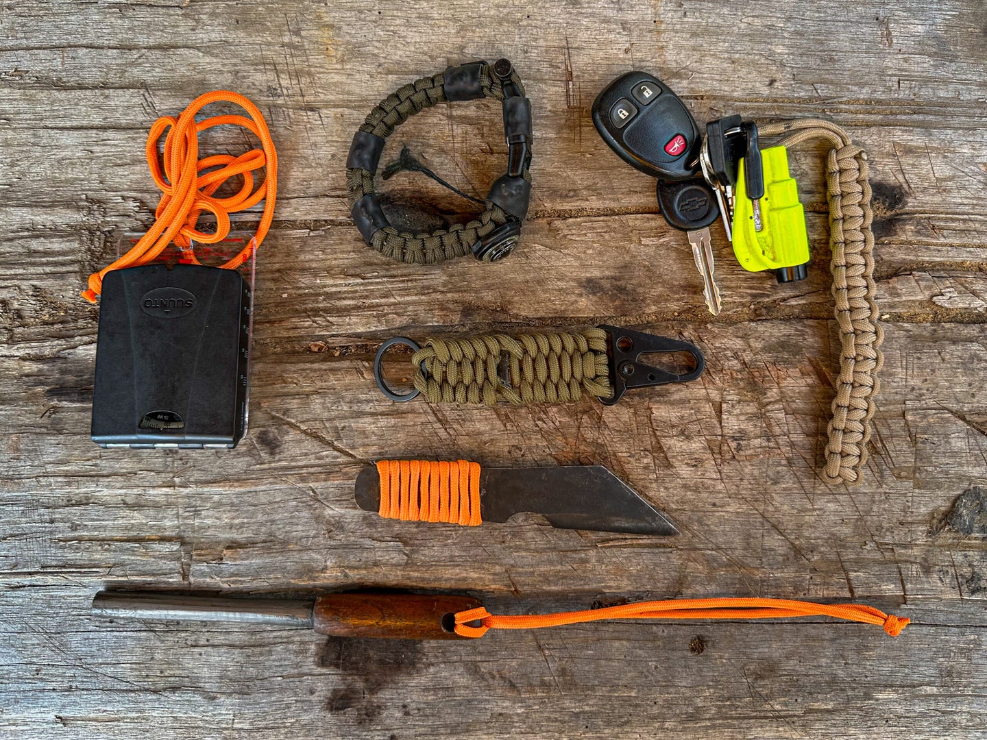 Various survival tools with parachute cord on a wooden surface