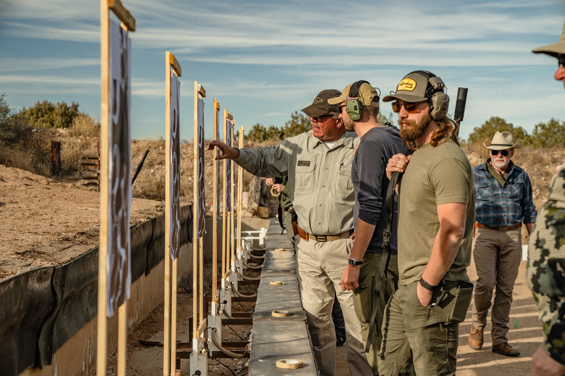 A group of shooters study their targets at a gun range.
