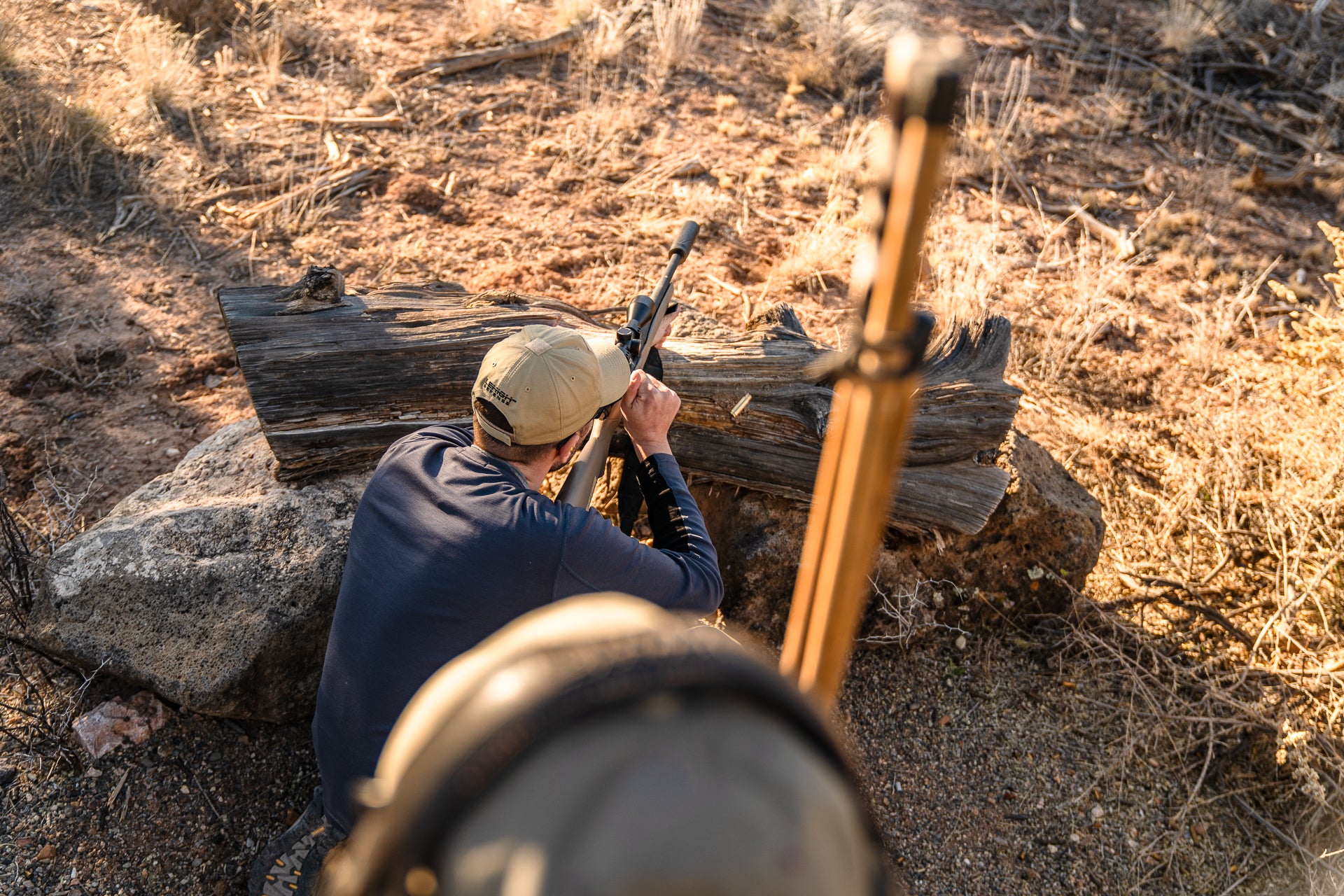 Above view of a shooter firing a rifle from a barricade at a gun range. 
