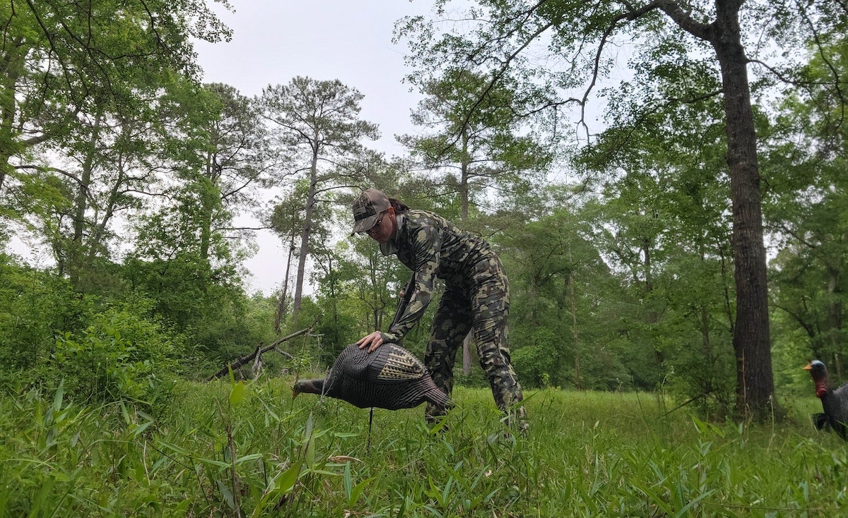Female turkey hunter wearing Forloh Insect Shield pants and shirt setting up decoys
