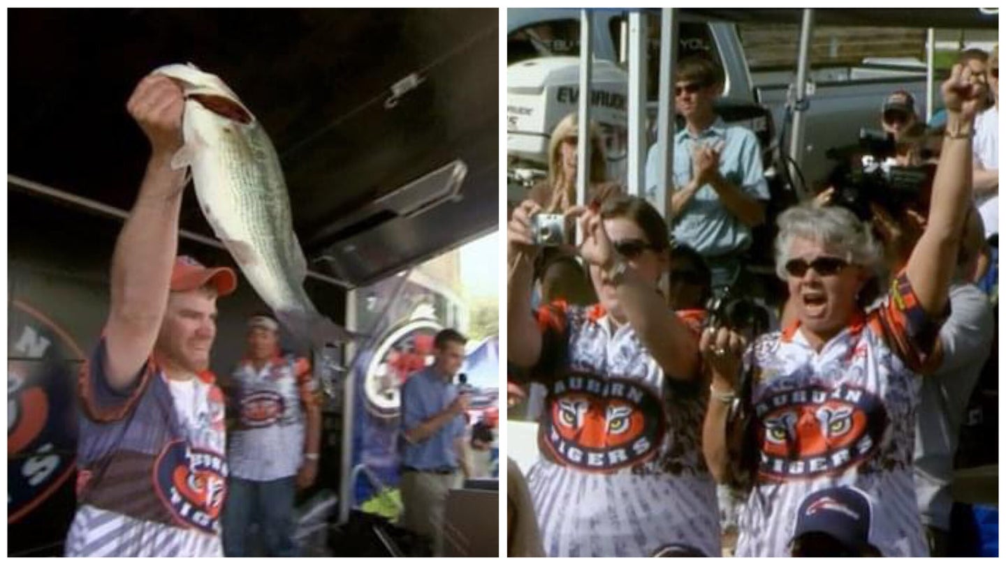 A bass fisherman holds a bass at a tournament, and fans cheer for him.
