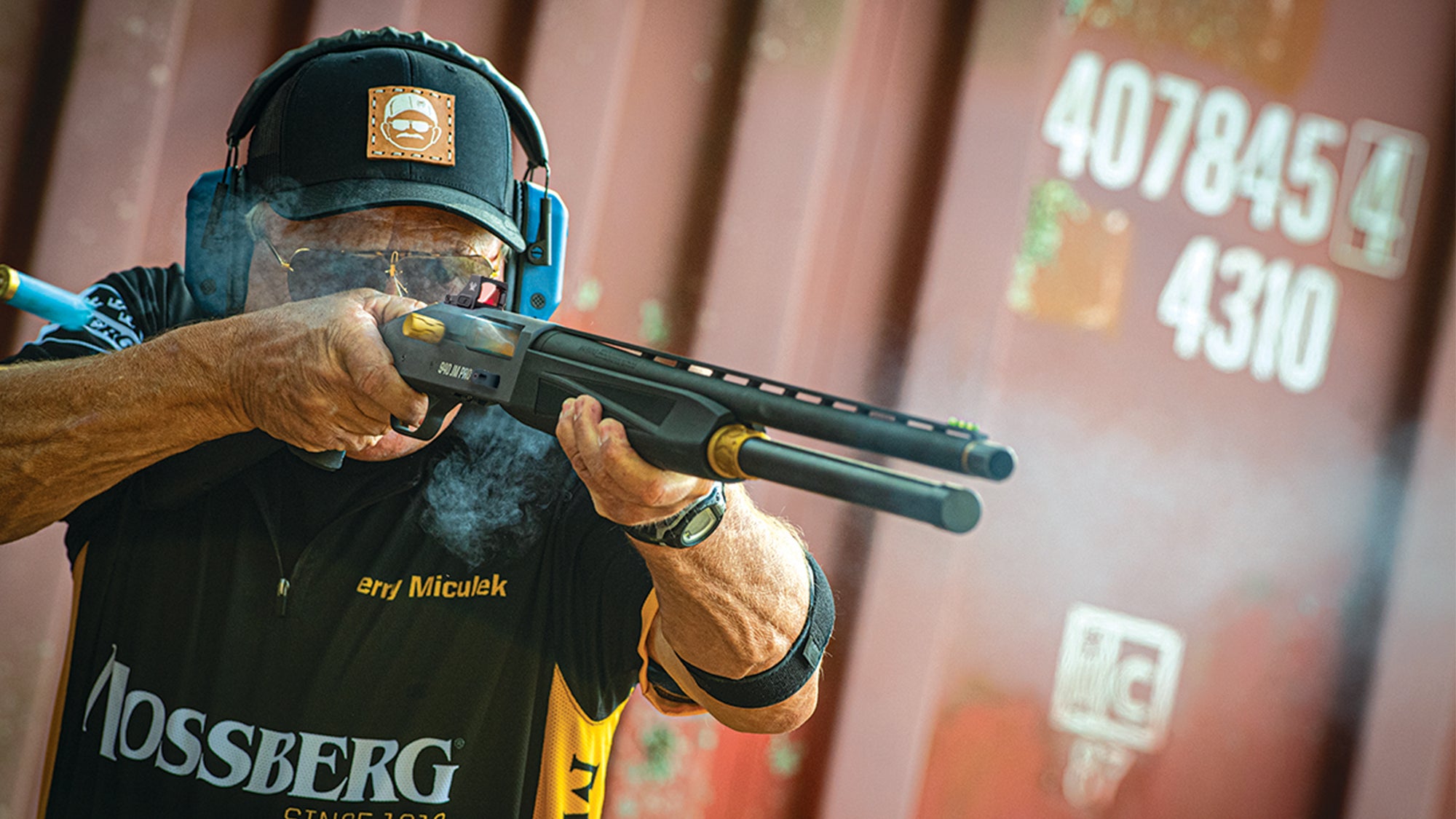 Pro shooter Jerry Miculek fires a Mossberg 940 shotgun at a shooting event.