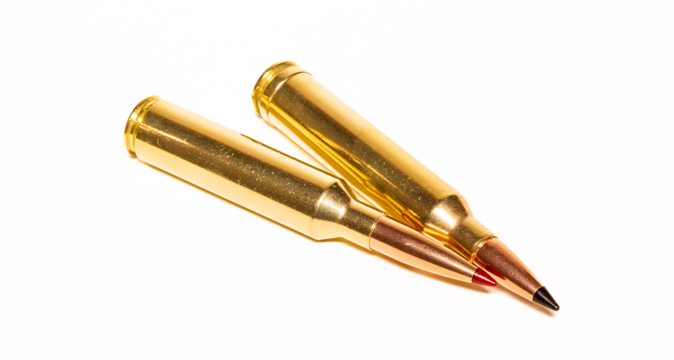 A 7 PRC cartridge and a 7mm Rem Mag cartridge lying next to each other on white background 