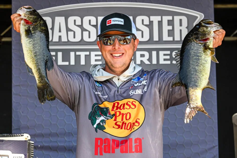 Pro angler Cody Huff holds up a pair of bass at a tournament weigh-in.