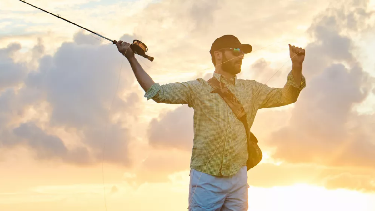 Fly fishing angler casting while wearing Orvis shirt