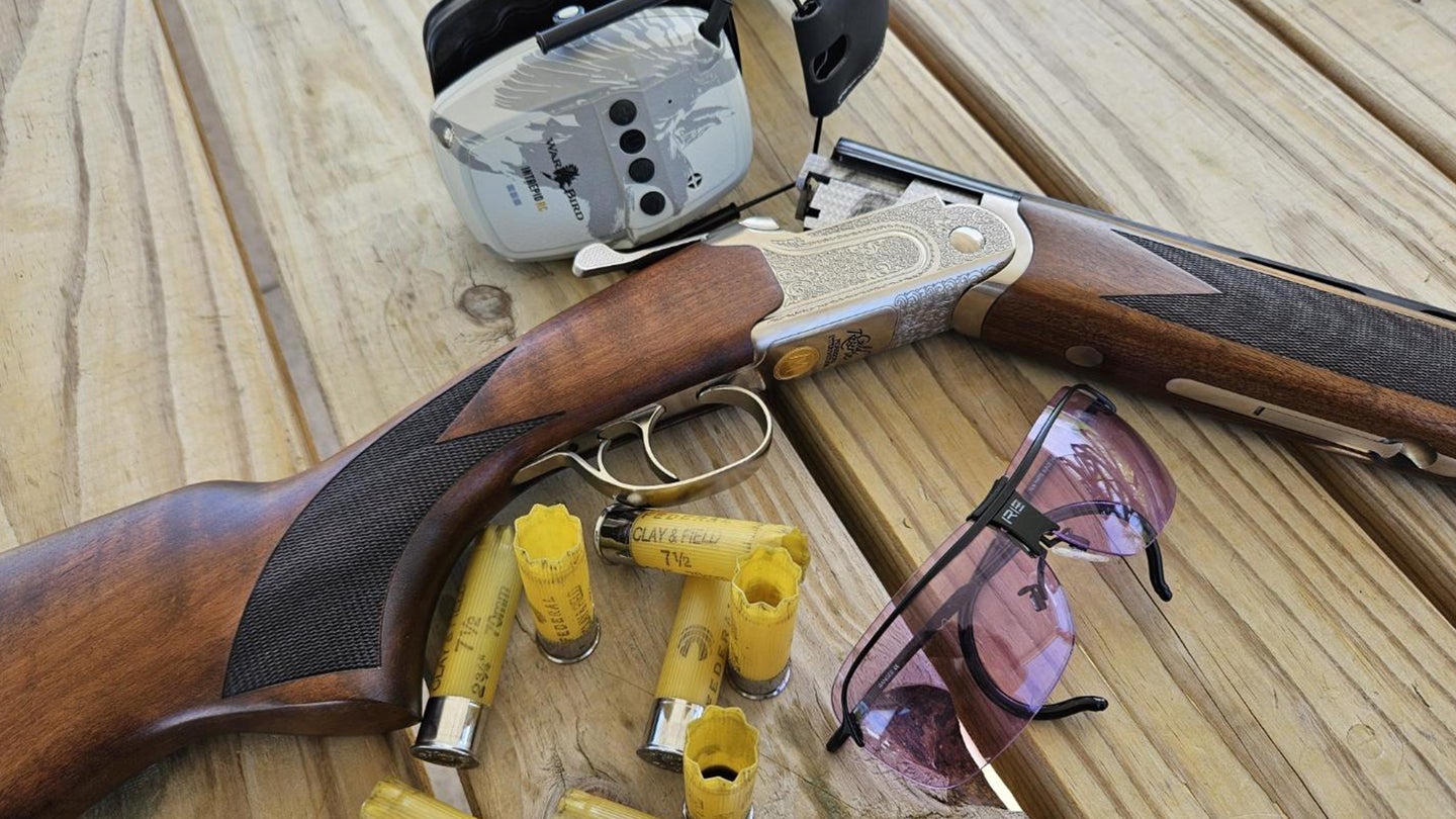 Mossberg Gold Reserve 20-Gauge Sporting over-under shotgun on a bench with shells and shooting glasses.